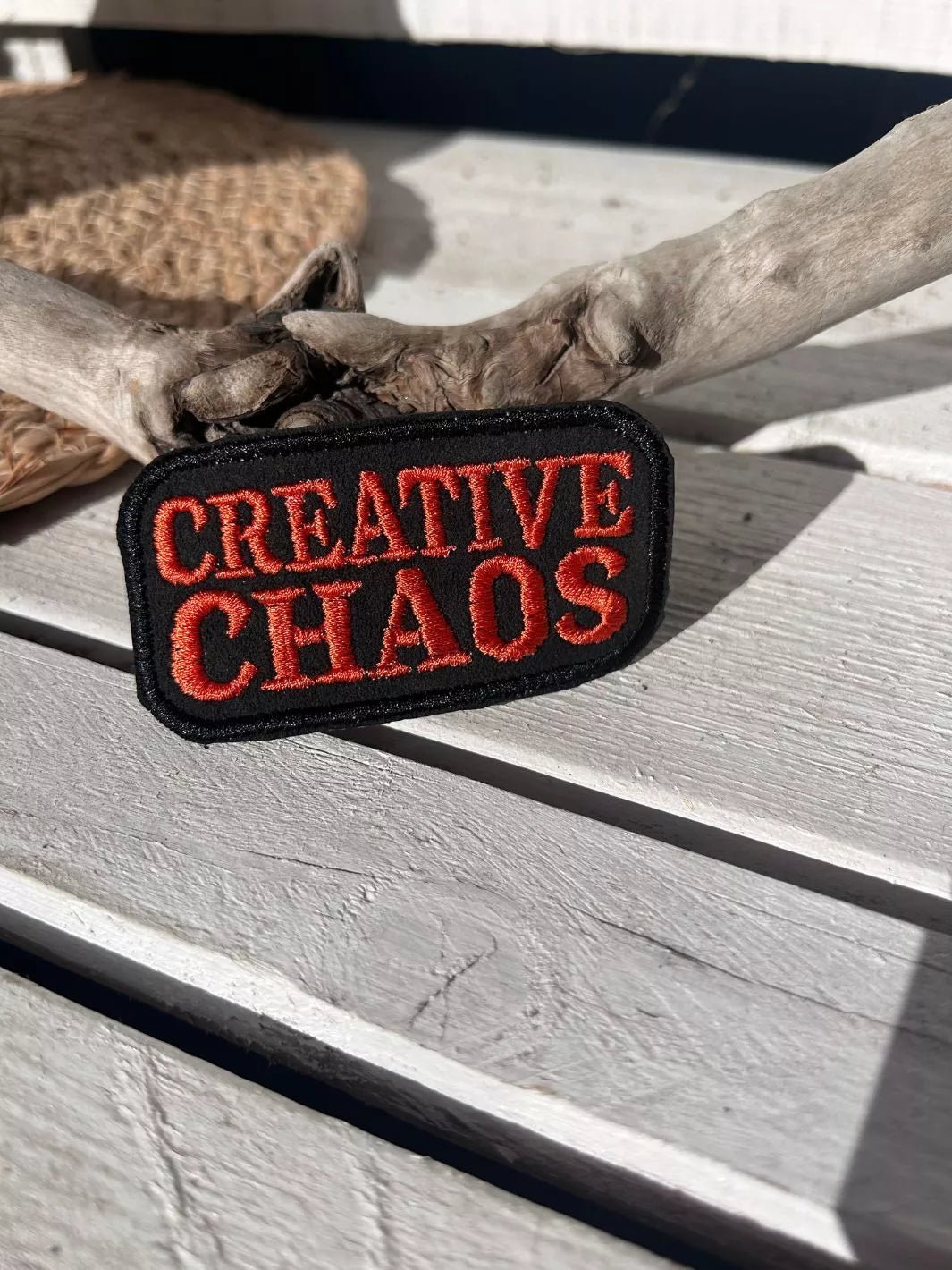 Creative Chaos embroidered iron-on patch with coral-red lettering on a black background