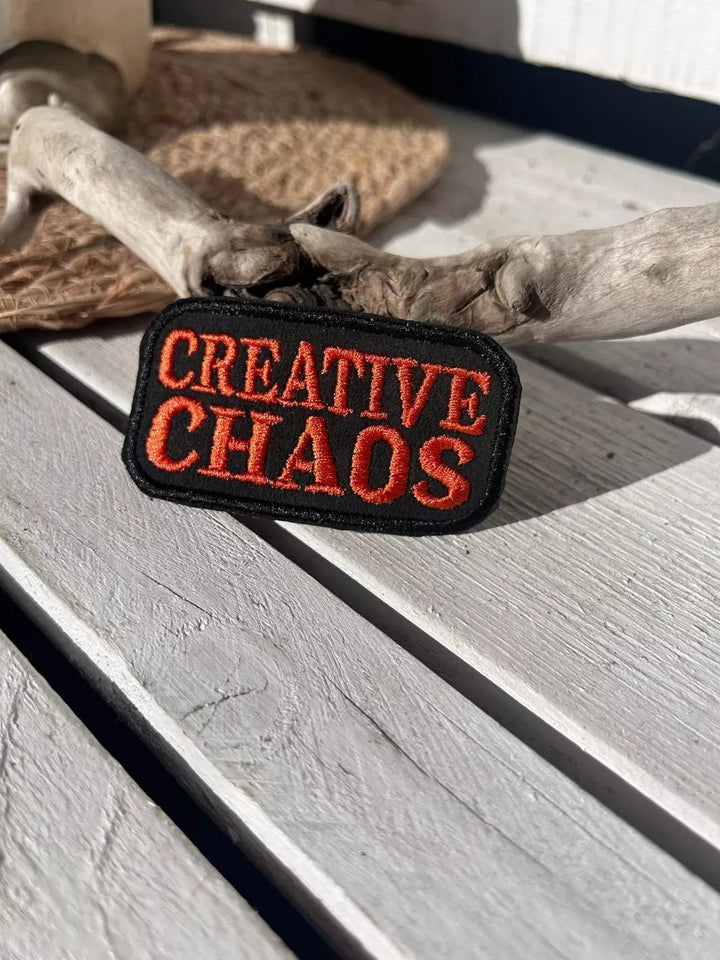 Creative Chaos embroidered iron-on patch with coral-red lettering on a black background