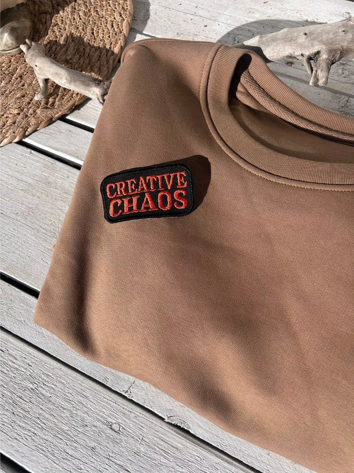 Creative Chaos embroidered iron-on patch with coral-red lettering on a black background