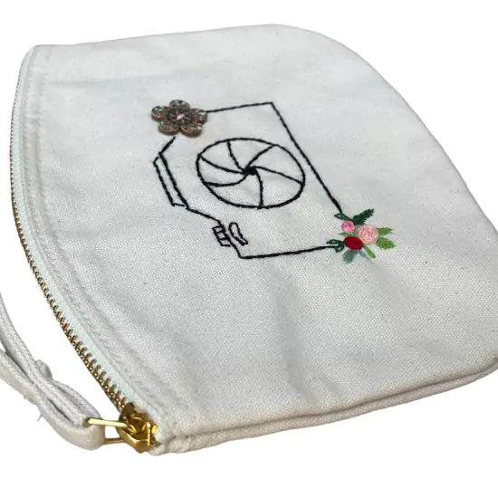 organic cotton clutch bag with a camera and flowers embroidered on it