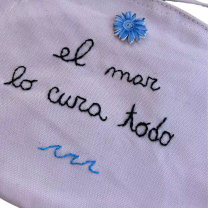 pink organic cotton clutch bag embroidered with the words "el mar lo cura todo"