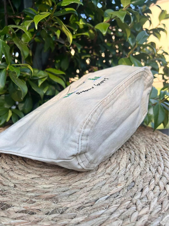 washed beige faded cotton travel pouch with embroidered cable car, pine trees, snow and Snow Lovers lettering