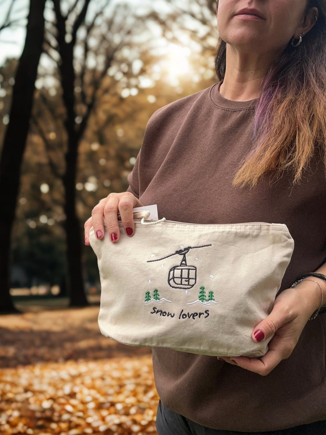 washed beige faded cotton travel pouch with embroidered cable car, pine trees, snow and Snow Lovers lettering
