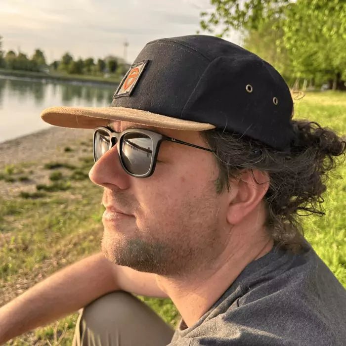 black snapback and with sand-colored visor with sewn patch with embroidered logo