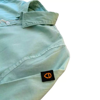 sage-colored organic cotton shirt with sewn military pocket and "explore" embroidered writing in the buttonhole