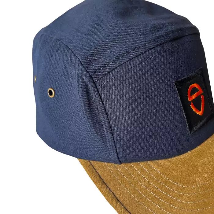 navy blue snapback and with a sand-colored visor with embroidered logo patch