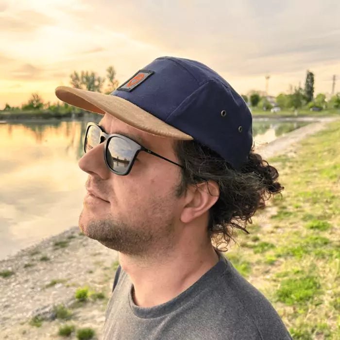 navy blue snapback and with a sand-colored visor with embroidered logo patch